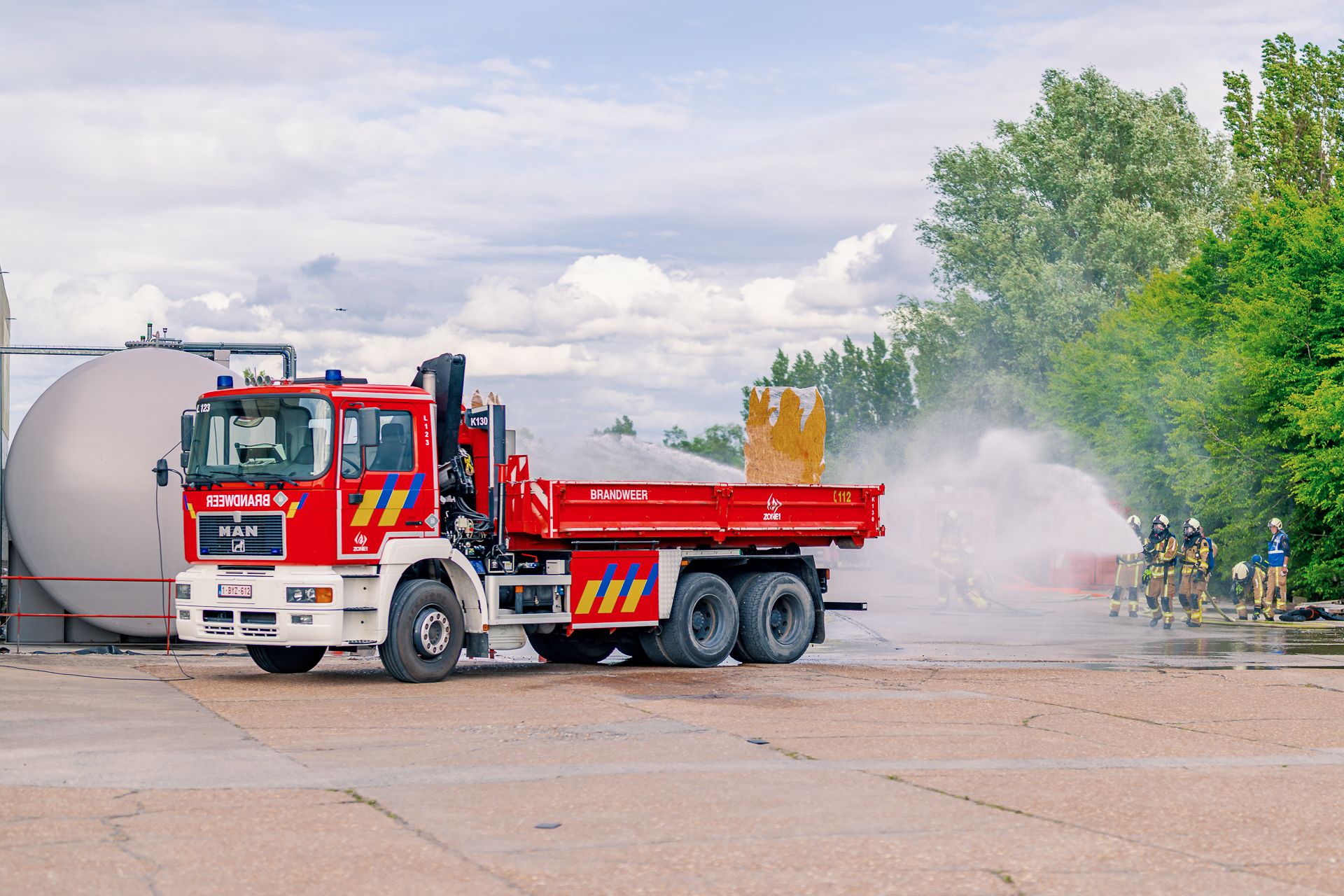 Brandweerwagen erachter staat de tank die de brandweermannen koelen.