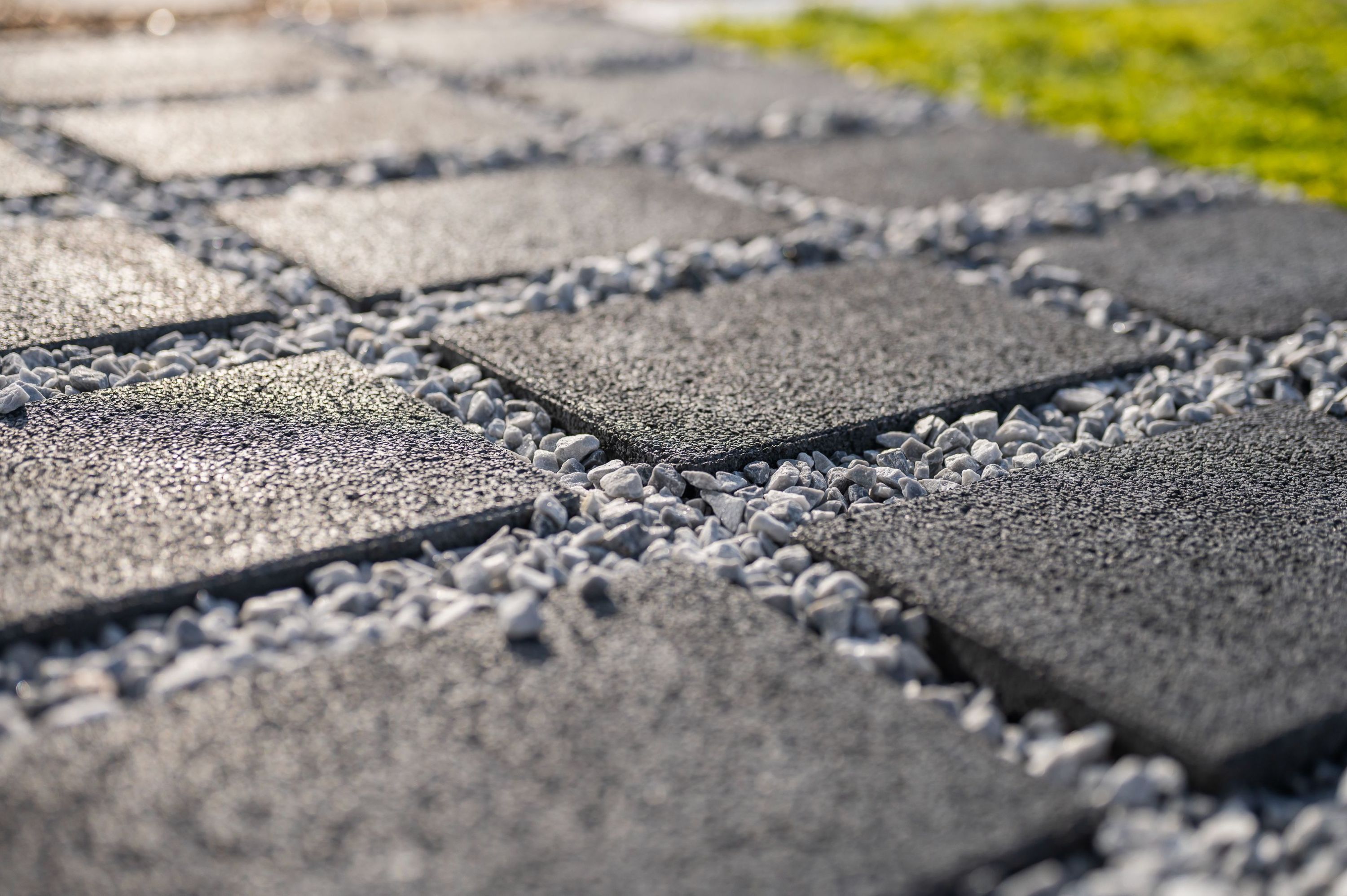 Close up waterdoorlatende verharding, zwarte vierkante klinkers met ertussen grijze steentjes.