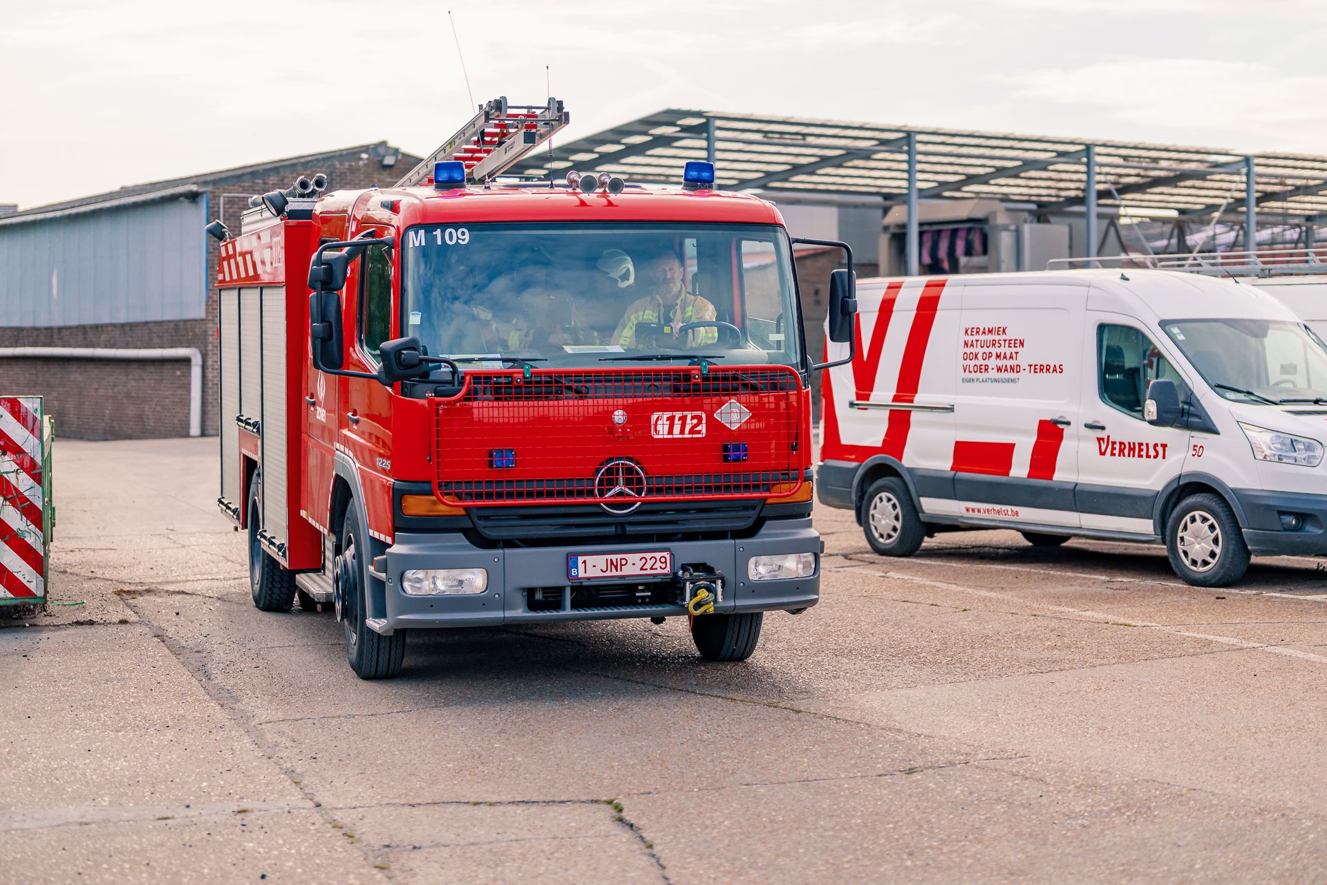 Frontaal zicht van de brandweerwagen die arriveert bij Groep verhelst.